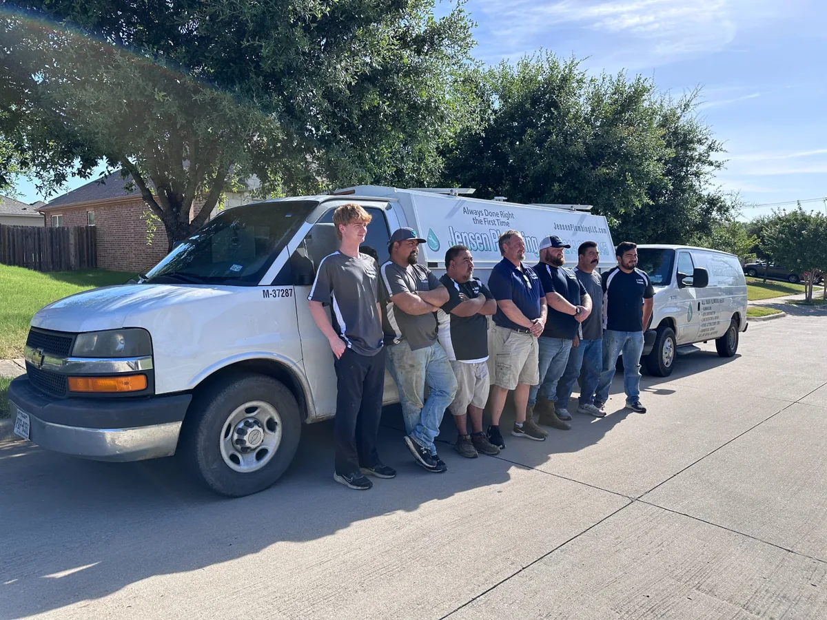 Jensen Plumbing crew standing with their branded service trucks